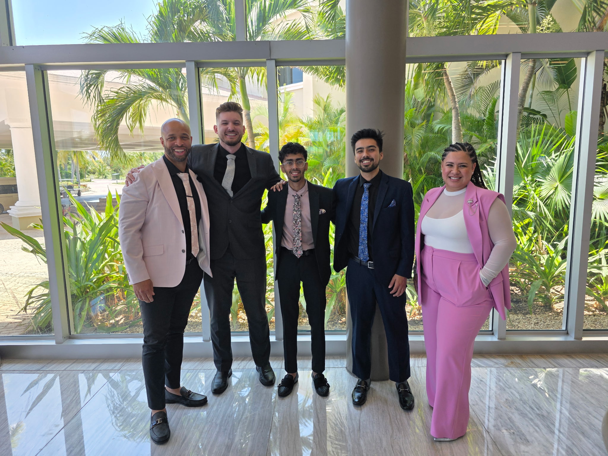 True Vision team of five professionals gathered in a bright atrium, smiling and engaged