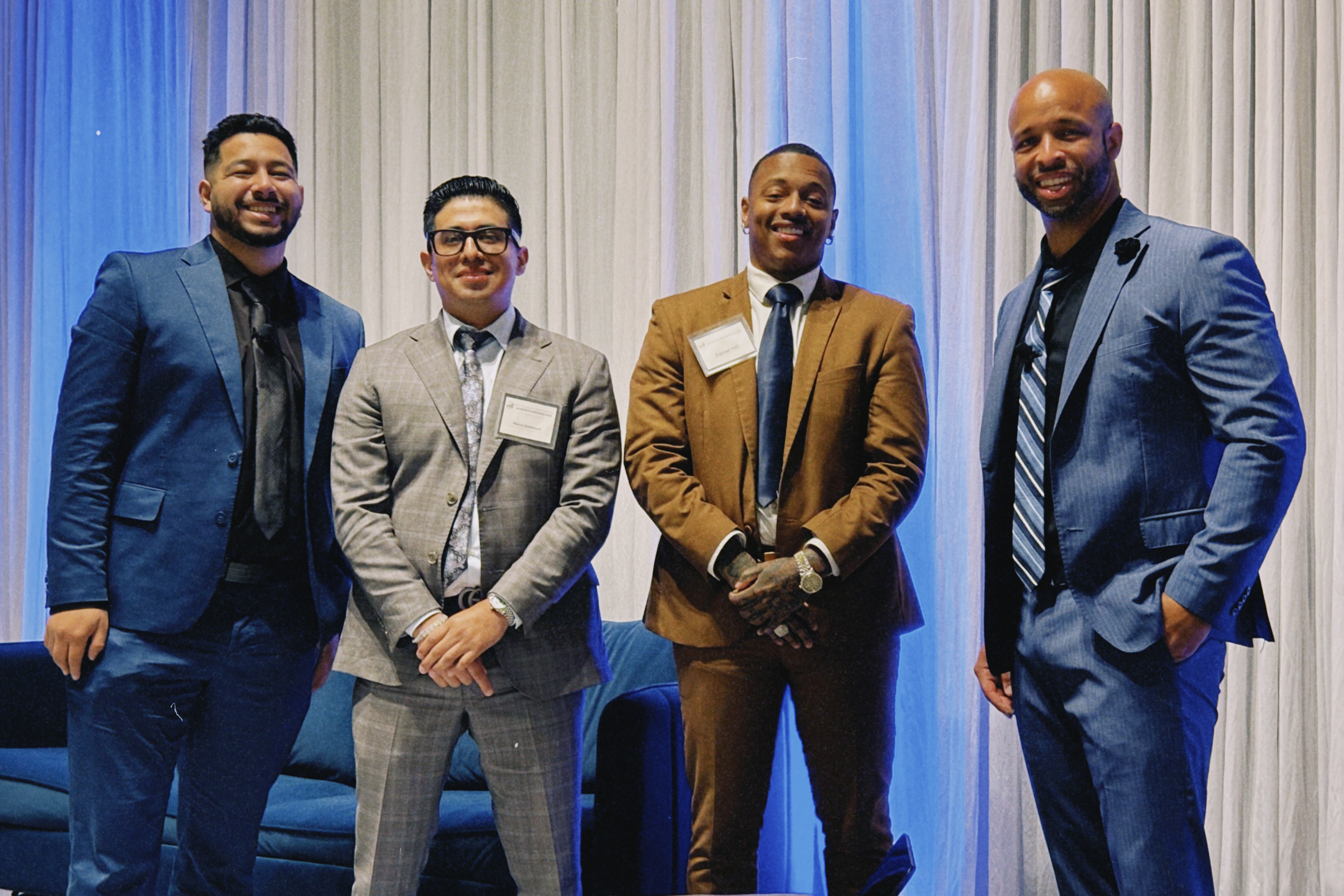 Four True Vision professionals in suits networking at a corporate event